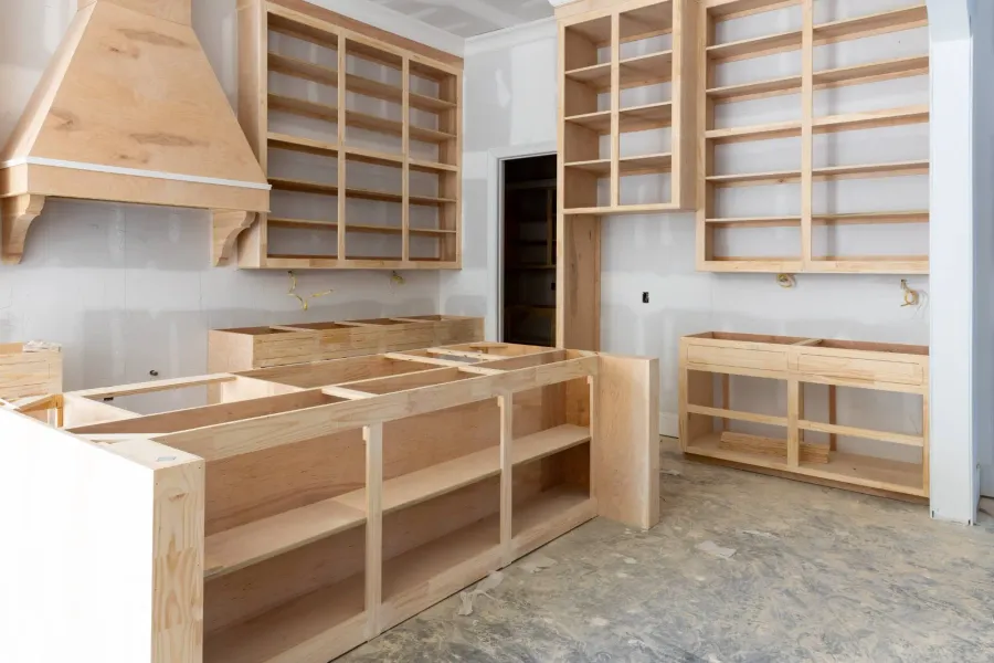 Cabinet boxes and shelving being installed in a kitchen under construction