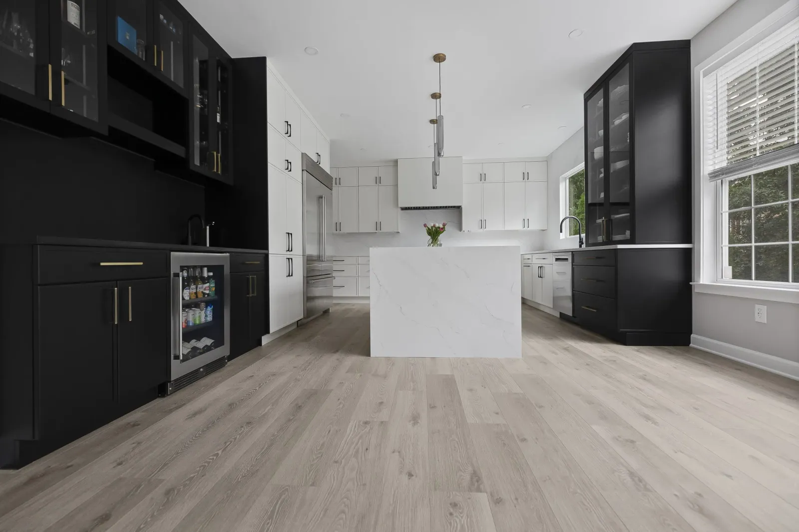 Finished kitchen with black and white cabinetry, a marble island and wood floors