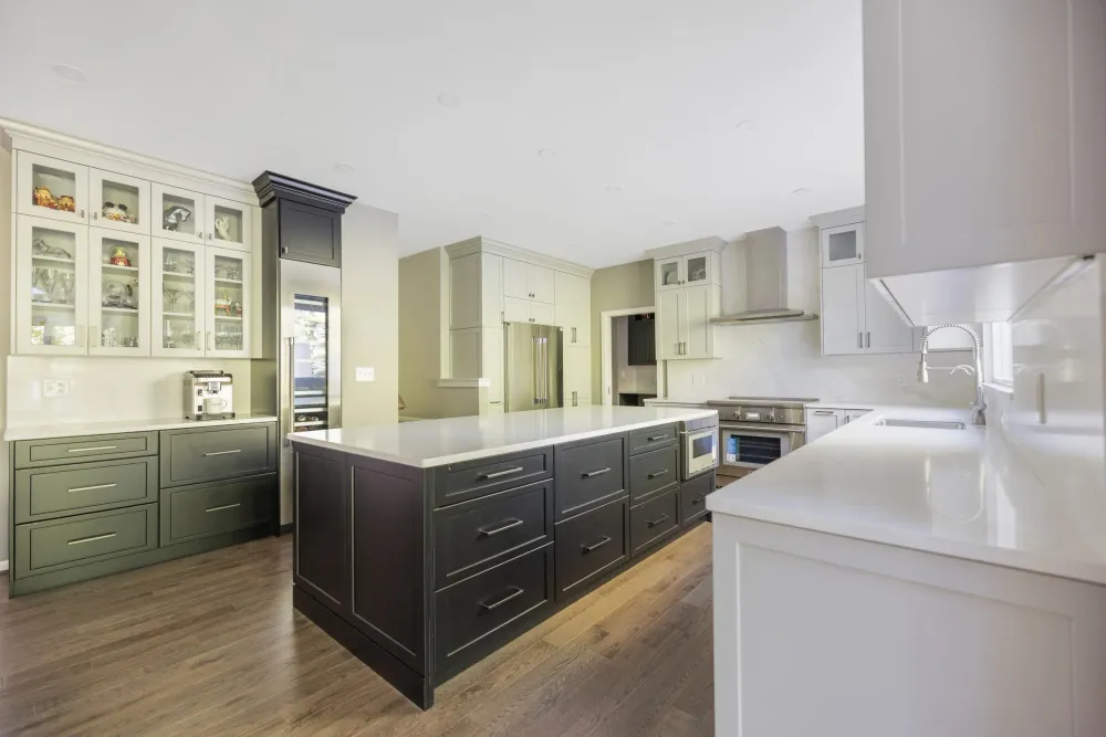Kitchen with white and dark green cabinetry, glass-front upper cabinets and a large island